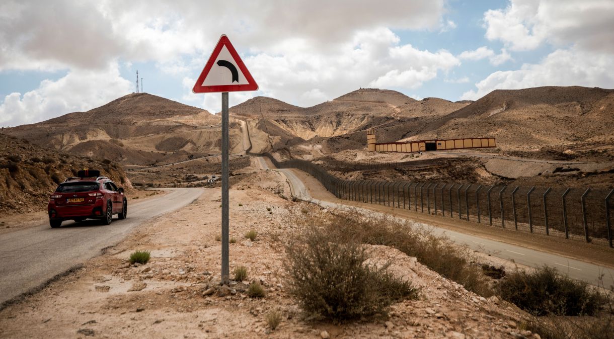 Um carro israelense circula em estrada monitorada por posto de controle militar egípcio na fronteira com Israel, visto do sul de Israel