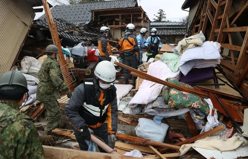 Bombeiros e membros da Força de Autodefesa do Japão resgatam um homem idoso de uma casa desabada em 3 de janeiro de 2024 em Suzu, Ishikawa, Japão.