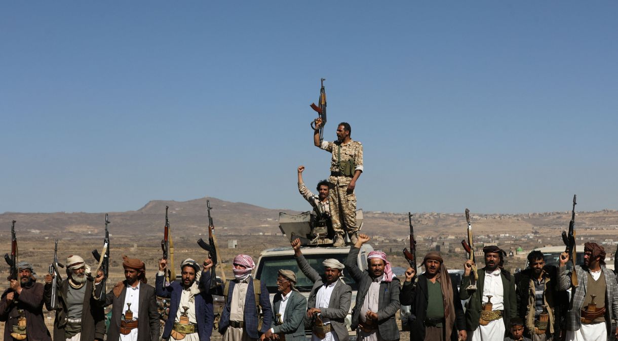 Combatentes houthis e apoiadores seguram suas armas durante protesto contra recentes ataques liderados pelos EUA contra alvos houthis, perto de Sanaa