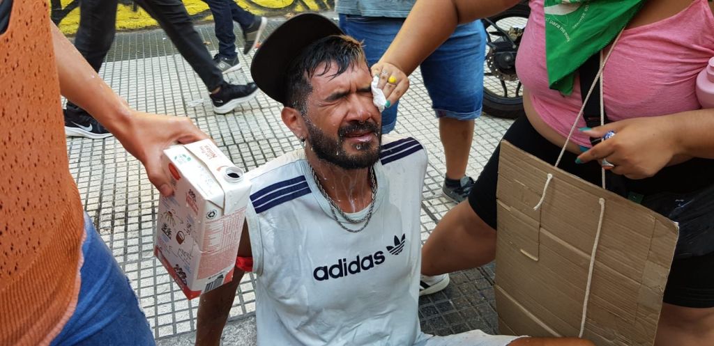 Manifestantes ajudam homem que não conseguia abrir os olhos após ser atingido por gás de pimenta durante protesto contra megaprojeto de Javier Milei