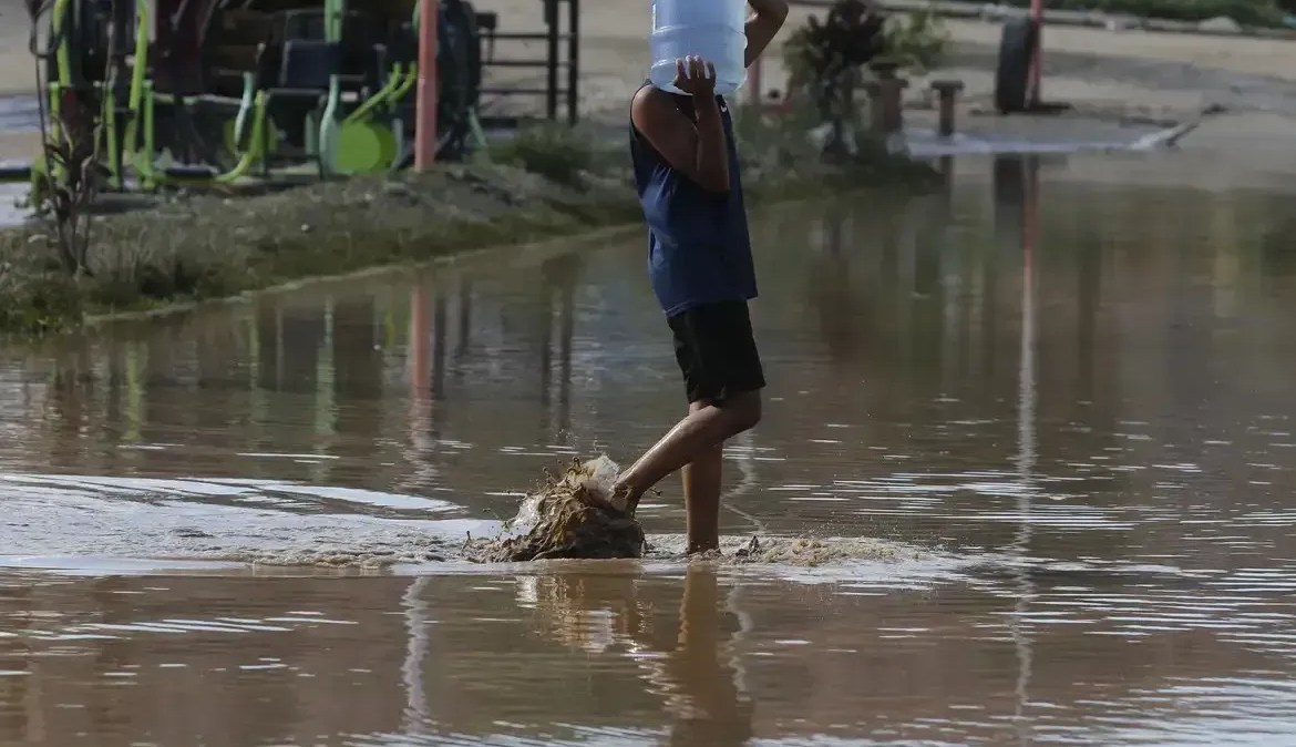 Homem anda em rua alagada; enchentes aumentam riscos de doenças graves