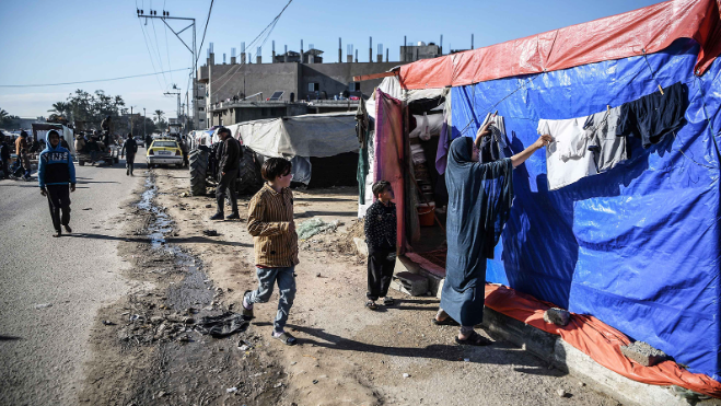 Palestinos deslocados são fotografados ao longo de uma estrada perto de sua tenda improvisada em Rafah, Gaza, em 4 de fevereiro