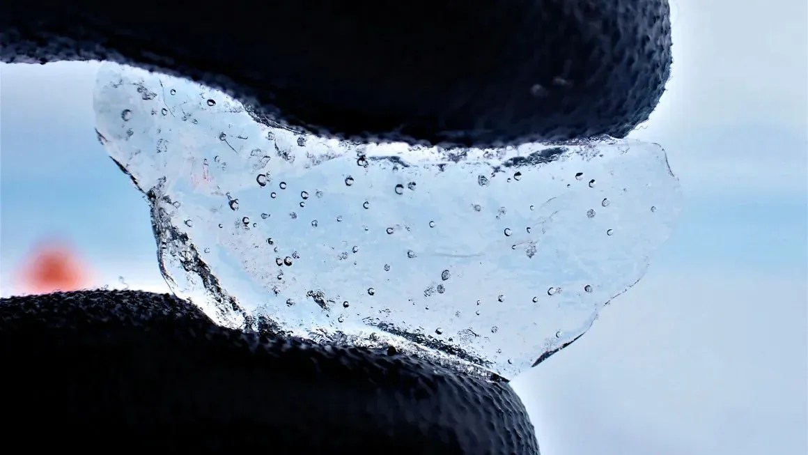 Cientista segura um pedaço de gelo perfurado na Antártica ocidental, mostrando as bolhas de ar presas dentro dele
