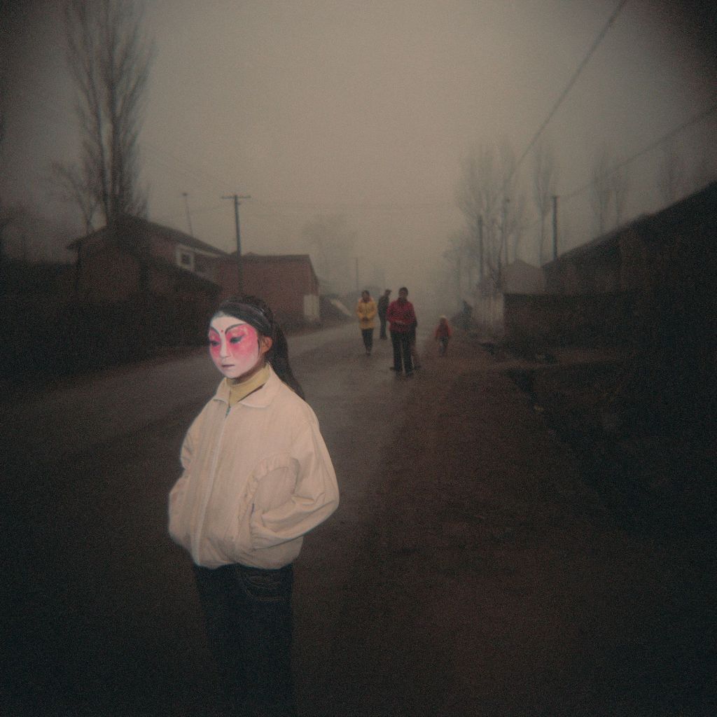 Menina mascarada antes de vestir a fantasia completa para as comemorações na vila de Huanghuayu, província de Shaanxi