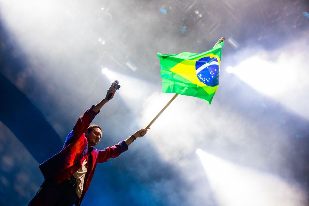 vocalista do arcade fire segurando a bandeira do brasil