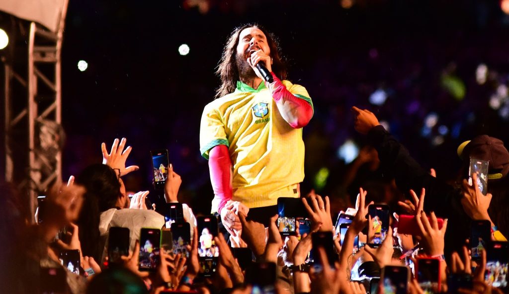 vocalista no meio da plateia usando a camisa da seleção