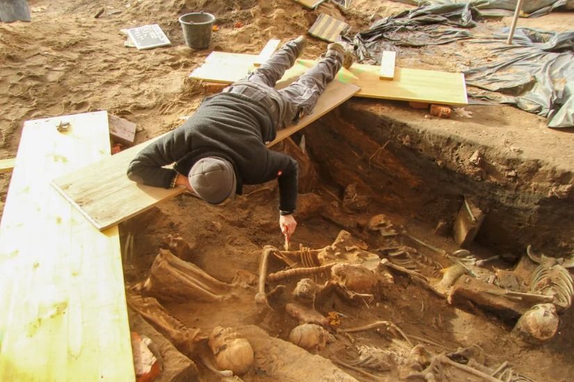 Arqueólogos trabalham em pontes improvisadas devido à alta densidade de sepultamentos.