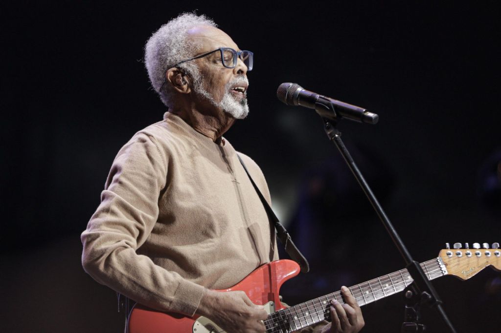 gilberto gil no palco tocando guitarra e cantando no microfone