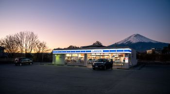 Ponto em frente a loja de conveniência é usado para fotos mostrando o contraste entre a movimentada loja iluminada por luzes neon e a pacífica montanha atrás dela