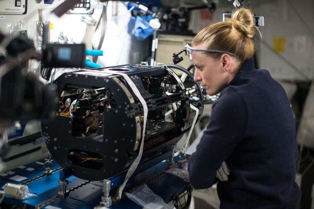 Astronauta Kate Rubins fazendo reparos em peças da Estação Espacial Internacional durante a Expedição 49, em 2016