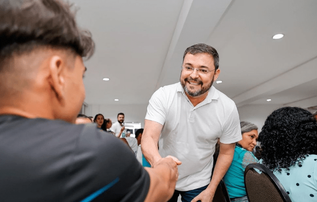 Fábio Novo (PT) aperta a mão de um homem. Ele sorri e veste uma camisa branca