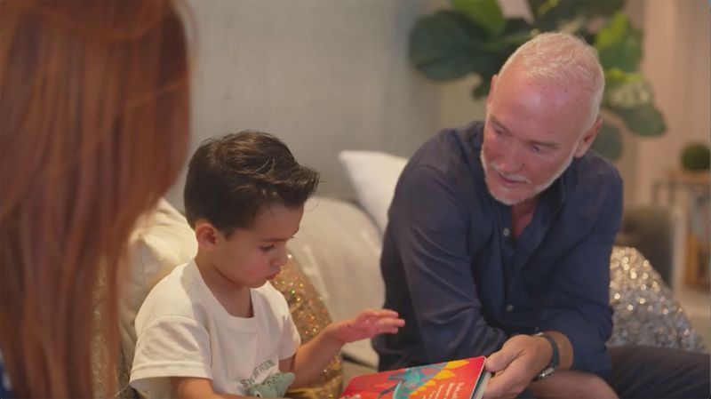Simon Nicholls lê um livro para o filho Sylver, de 3 anos, na casa deles em Miami