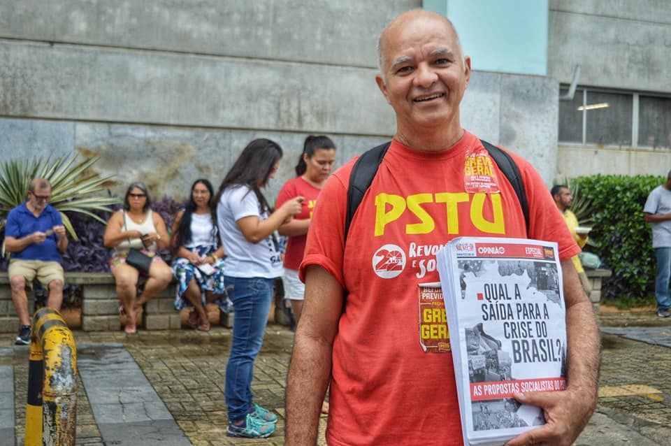 Nando Poeta veste camisa vermelha. É idoso e branco.