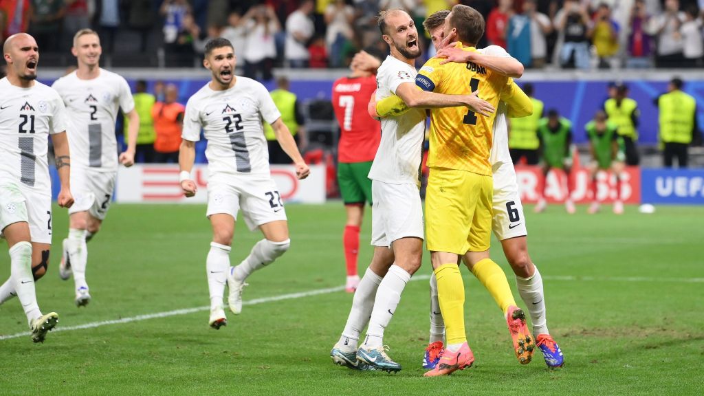 Oblak comemora defesa de pênalti com jogadores da Eslovênia, enquanto Cristiano Ronaldo lamenta ao fundo