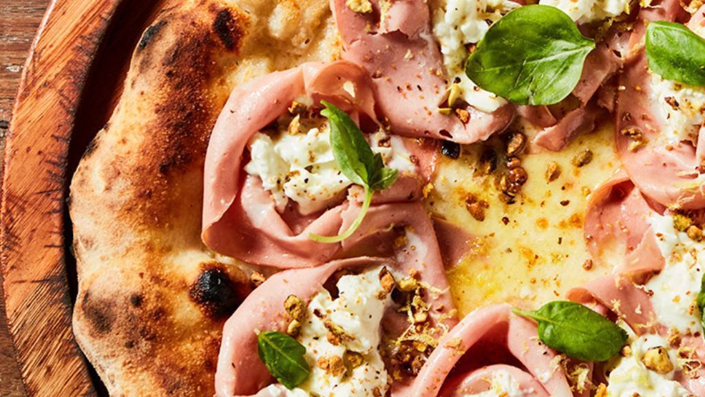 Pizza Bologna tem mortadela italiana, fior di latte, stracciatella, pistache, manjericão e raspas de limão siciliano