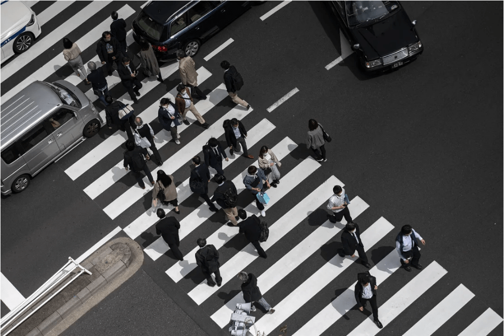 Pedestres, incluindo funcionários de escritório, atravessam uma rua na área de Shimbashi, em Tóquio, na hora do almoço, em 1º de abril de 2021. 