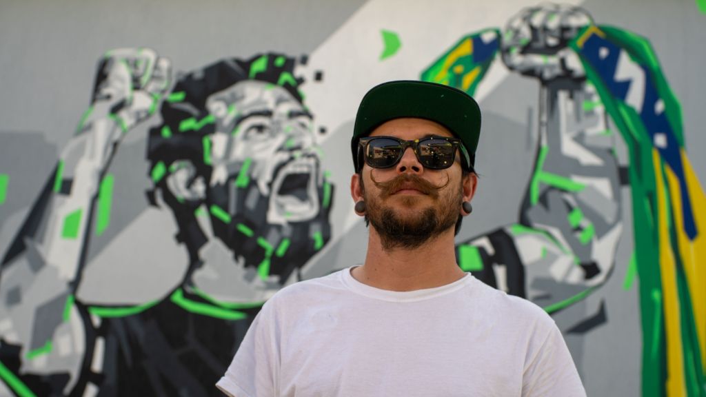 Muralista e artista de rua Arlin Graff com a arte que fez em Jacarepaguá, Zona Oeste do Rio de Janeiro, em homenagem a FalleN e a história do Counter-Strike no Brasil