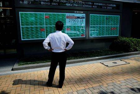 Homem observa painel eletrônico com cotações do mercado financeiro.