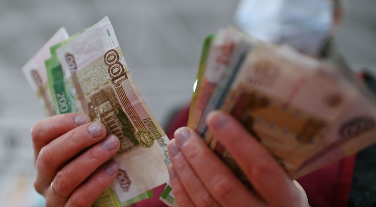Vendedor conta notas de rublos em mercado de Omsk, Rússia