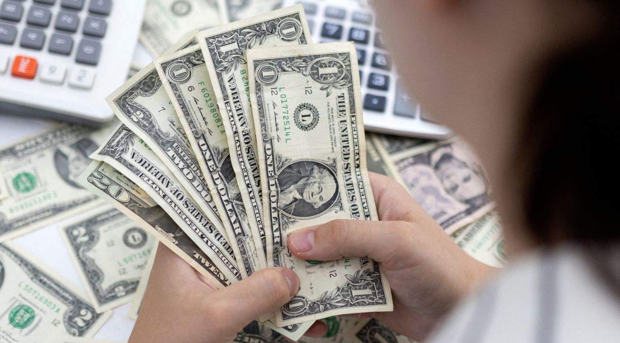 Mulher seguNa véspera, o dólar à vista fechou o dia cotado a R$ 5,0588 na vendara notas de dólares