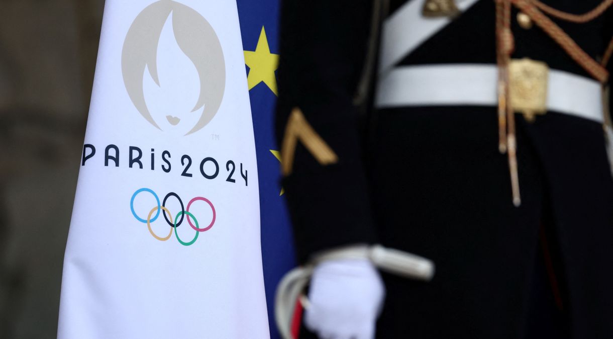 Integrante da Guarda Republicana Francesa ao lado da bandeira dos Jogos Olímpicos de Paris 2024, na entrada do Palácio do Eliseu, em Paris, França