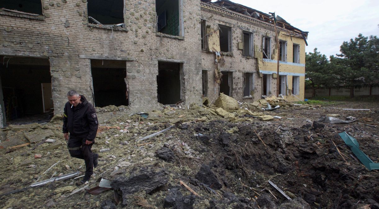 Policial caminha ao lado de prédio de escola danificado por ataque russo na região ucraniana de Donbass