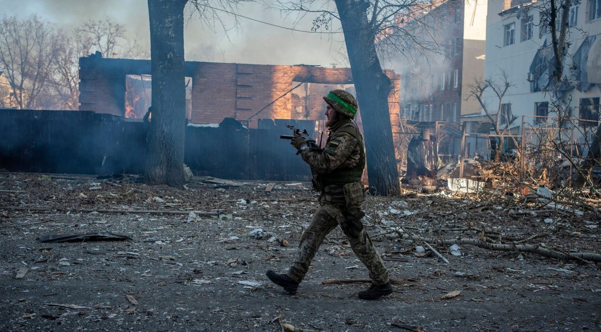 Soldado ucraniano caminha em frente a prédio em chamas na cidade de Bakhmut, na linha de frente da guerra