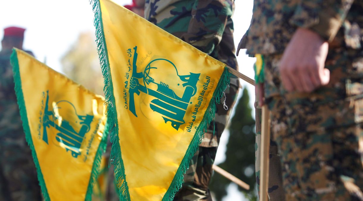 Membros do Hezbollah seguram bandeiras com o símbolo do grupo próximos à fronteira de Israel
