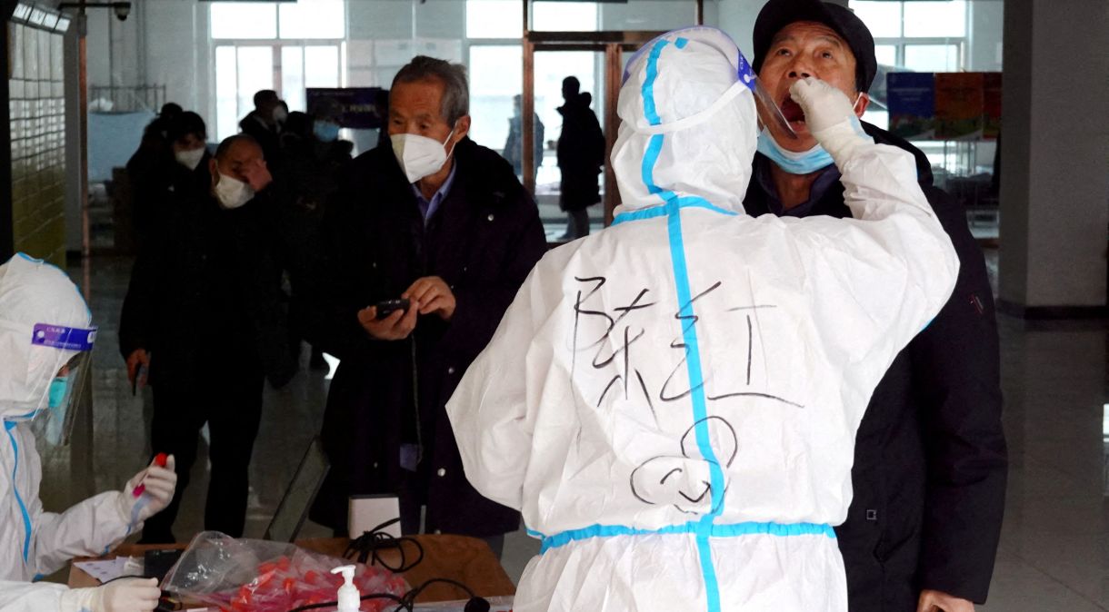 Agente de saúde com roupa de proteção faz teste de Covid-19 em morador de complexo residencial em Xian, na China: Crise no país também é um problema para o mundo