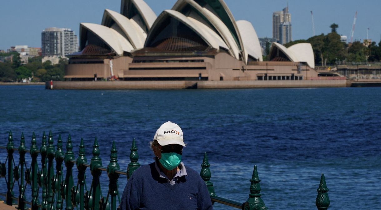 Homem com máscara caminha em frente à Casa da Ópera de Sydney; Austrália registra crescimento dos casos de Covid-19