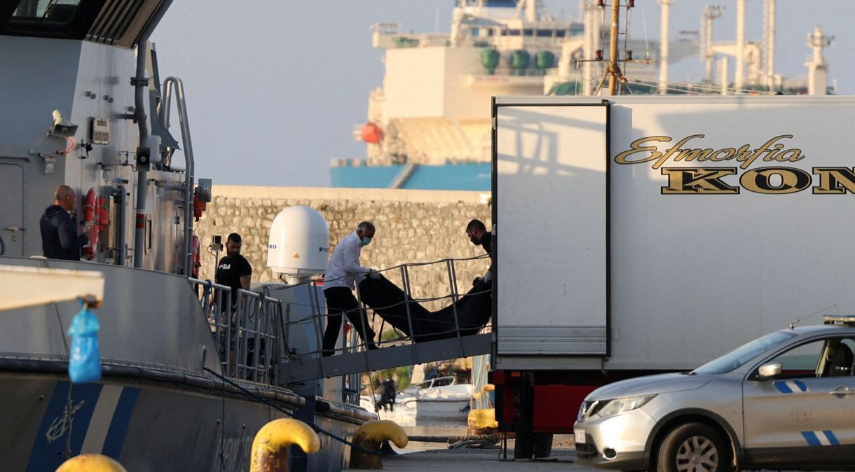 Homens carregam malas com corpos de imigrantes mortos em embarcação, em Kalamata, Grécia