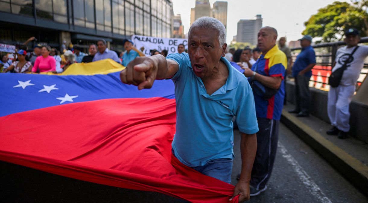 Pessoas seguram bandeira da Venezuela durante protesto em Caracas contra governo do presidente Nicolás Maduro