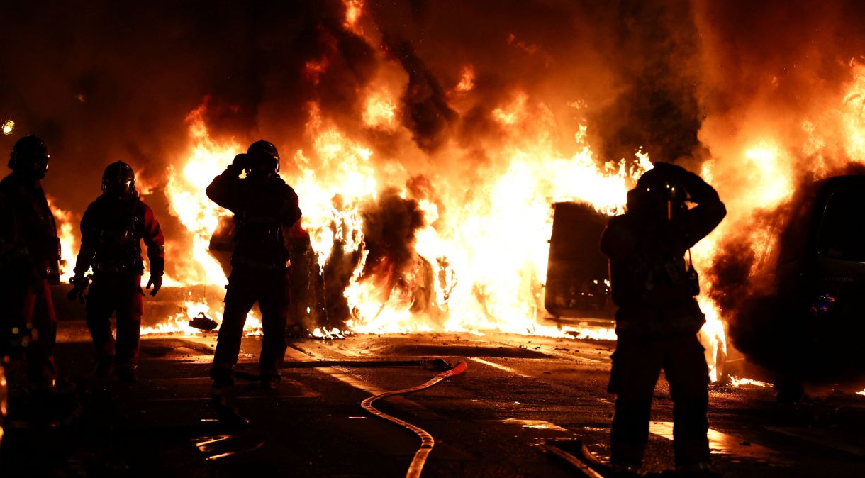 Bombeiros trabalham em meio a carros incendiados durante confrontos entre manifestantes e policiais, em Paris, França