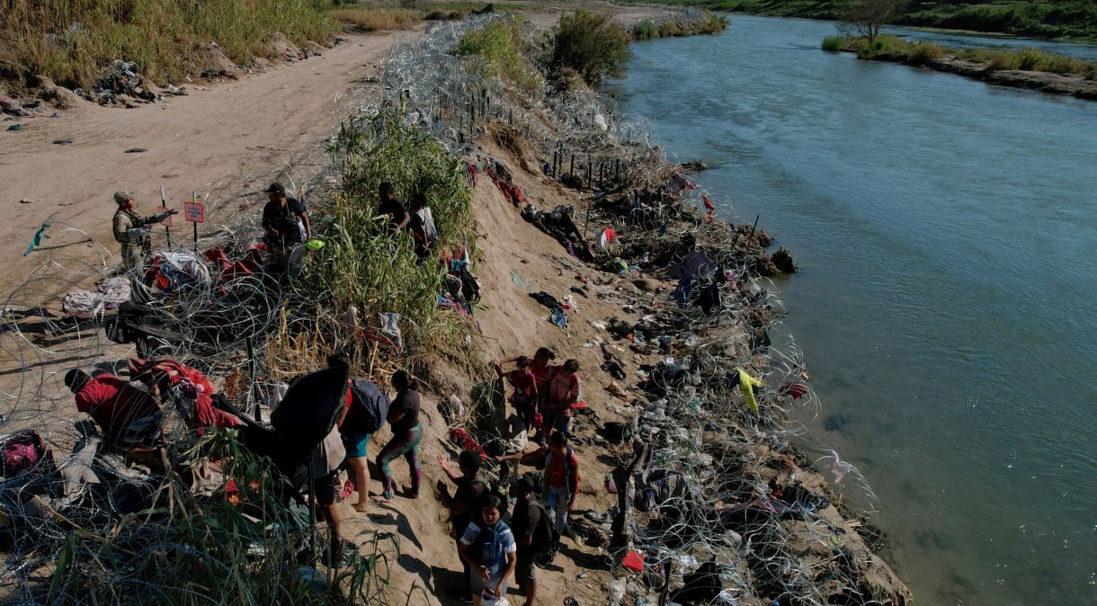 Membros da Guarda Nacional do Texas tentam dissuadir migrantes de atravessar cerca depois de terem cruzado o Rio Grande na fronteira com o México