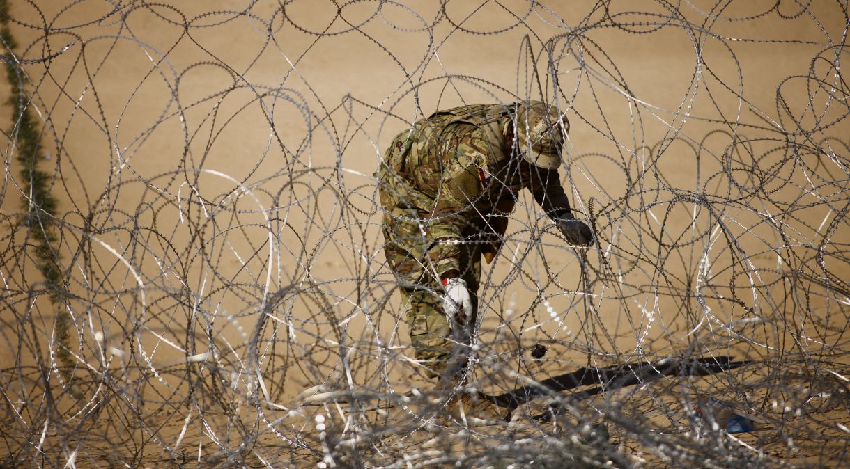 Membro da Guarda Nacional do Texas trabalha em cerca de arame farpado perto de muro na fronteira entre Estados Unidos e México