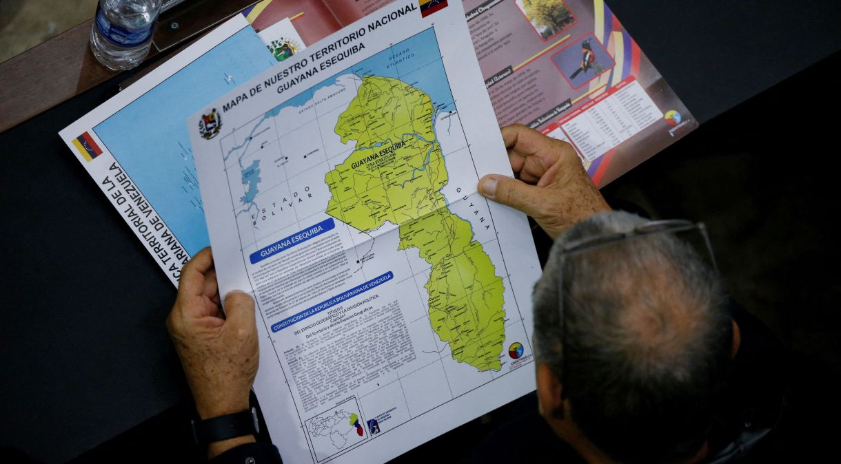 Membro da Assembleia Nacional segura mapa que mostra a disputada região de Esequibo como parte da Venezuela em Caracas