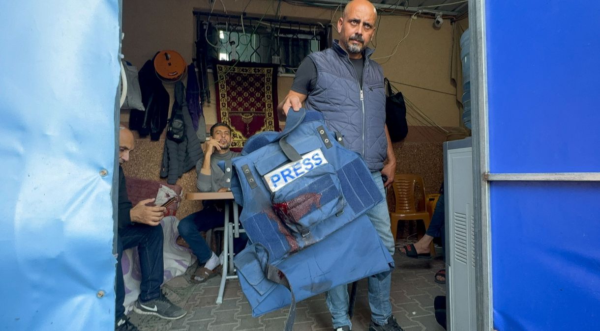 Homem segura colete de proteção pertencente a Wael Al-Dahdouh, jornalista da Al Jazeera, em Khan Younis, no sul da Faixa de Gaza