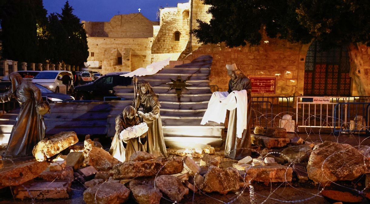 Figuras religiosas em meio a escombros e cercadas por arame farpado, como forma de apoio a Gaza, do lado de fora da Igreja da Natividade, na Praça da Manjedoura, em Belém, na Cisjordânia ocupada por Israel