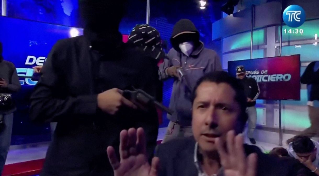 Homem encapuzado aponta arma para apresentador de TV equatoriano José Luis Calderon durante transmissão na estação de televisão TC do Equador