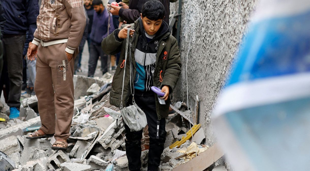 Civis caminham sob escombros após ataque em Rafah