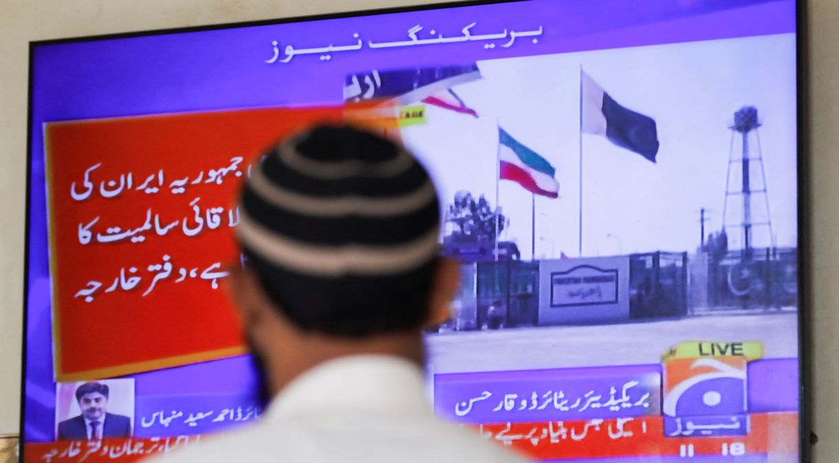 Homem observa TV após ataque do Paquistão dentro do Irã