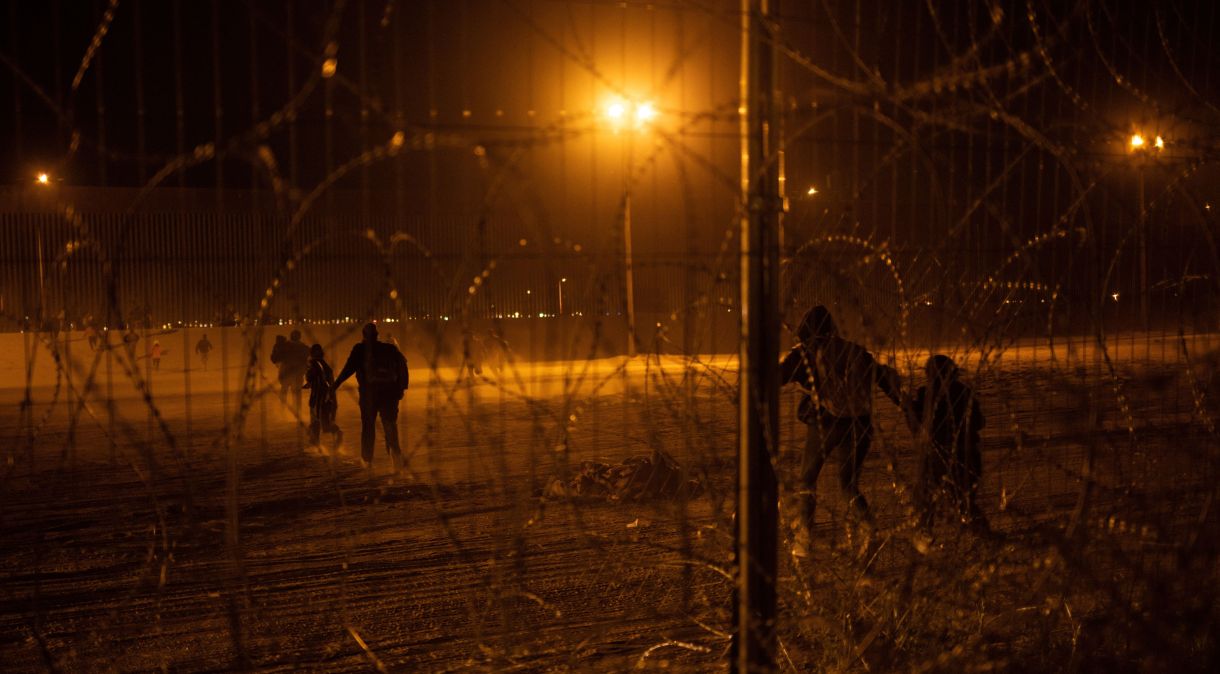 Migrantes correm em direção ao muro da fronteira após quebrar cerca na entrada do México para os EUA