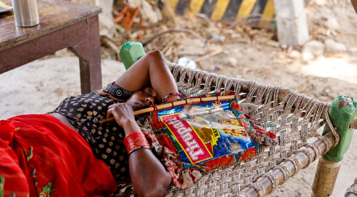 A trabalhadora agrícola Khilona, ​​de 50 anos, dorme em cama com leque feito à mão sob um galpão em sua casa, nas planícies aluviais de Yamuna, em um dia quente de verão durante onda de calor