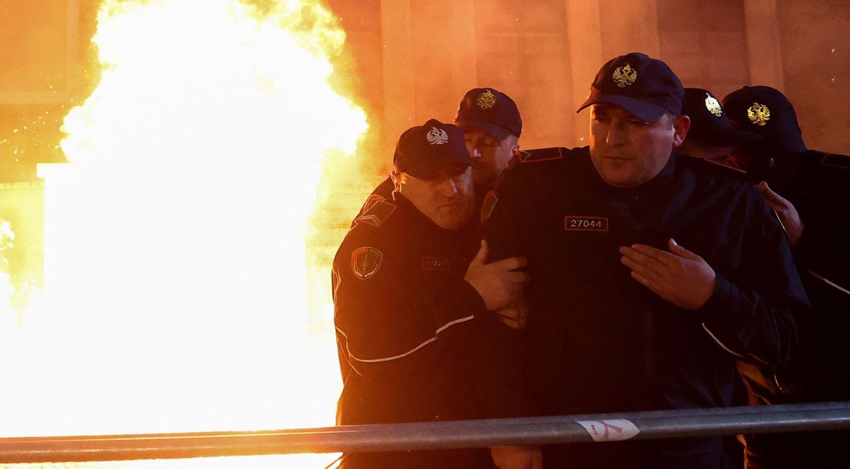 Policiais protegem-se de fogo durante protesto antigovernamental em frente ao gabinete do primeiro-ministro Edi Rama em Tirana, Albânia