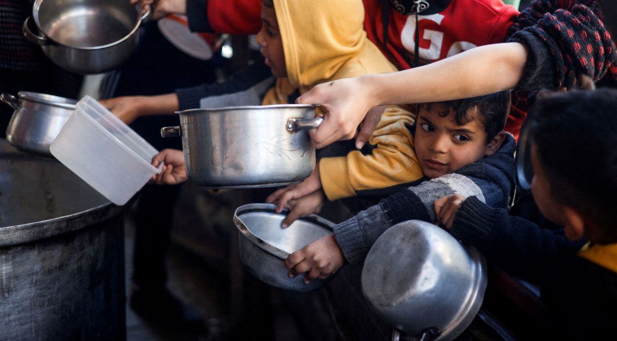 Crianças palestinas aguardam para receber comida de uma cozinha de caridade em meio à escassez de suprimentos, em Rafah, sul da Faixa de Gaza