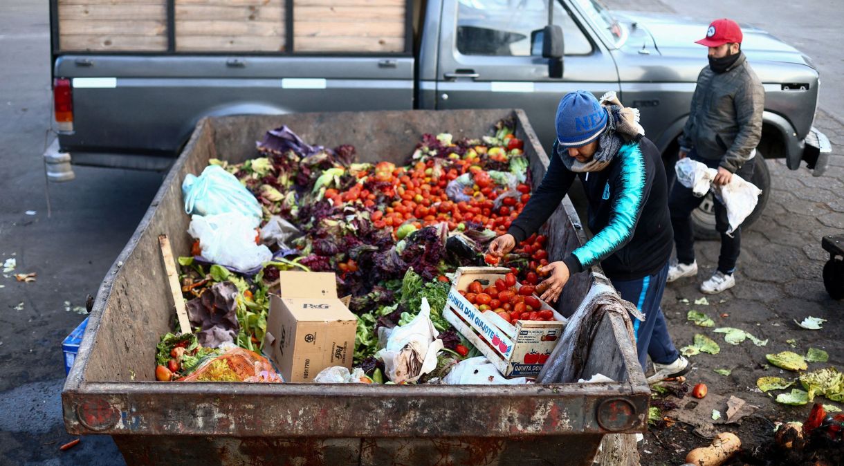 Homem recolhe comida em contêiner onde alimentos são descartados no Mercado Central de Buenos Aires