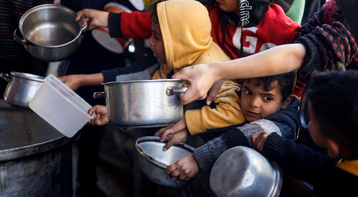 Crianças palestinas esperam comida preparada em cozinha de caridade em meio à escassez de alimentos, em Rafah, na Faixa de Gaza
