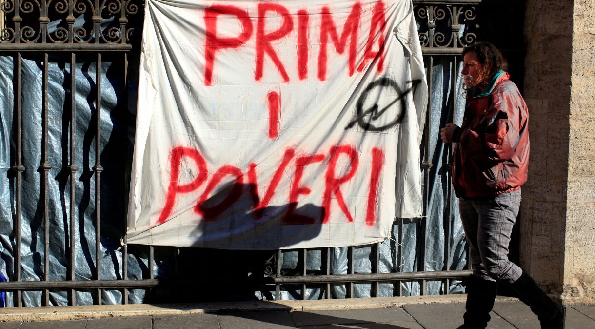 Faixa com frase "Pobres primeiro", pendurada em portão do pórtico da Basílica dos Santos Apóstolos, em Roma, Itália
