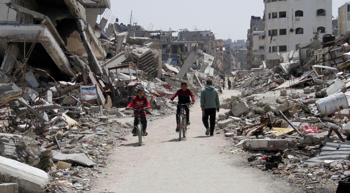 Palestinos andam de bicicleta pelas ruínas de casas e edifícios, destruídos durante a ofensiva militar de Israel na Faixa de Gaza