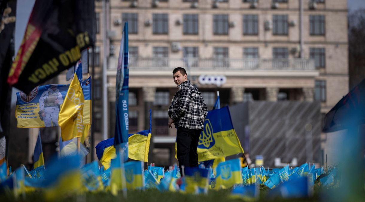 Homem passa por bandeiras ucranianas em memorial, em Kiev, em homenagem aos militares mortos que lutaram contra a invasão da Ucrânia pela Rússia